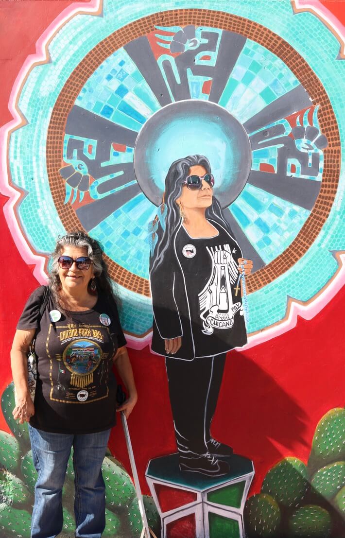 Chicano Park activist, Tommie Camarillo, posed with a mural that a local artist painted of her in homage of her commitment to the preservation and celebration of the park and immigrant rights at the border.