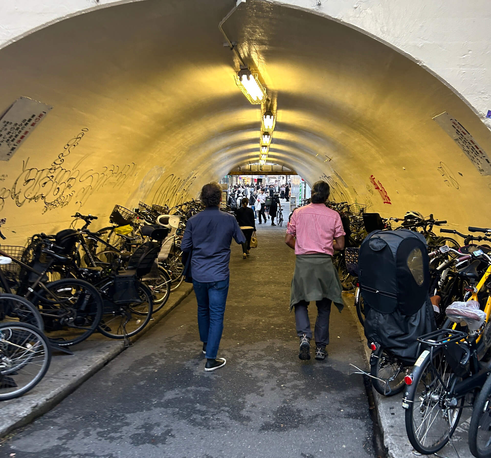 John and Adi walking through pedestrian tunnel lined with hundreds of parked bikes.