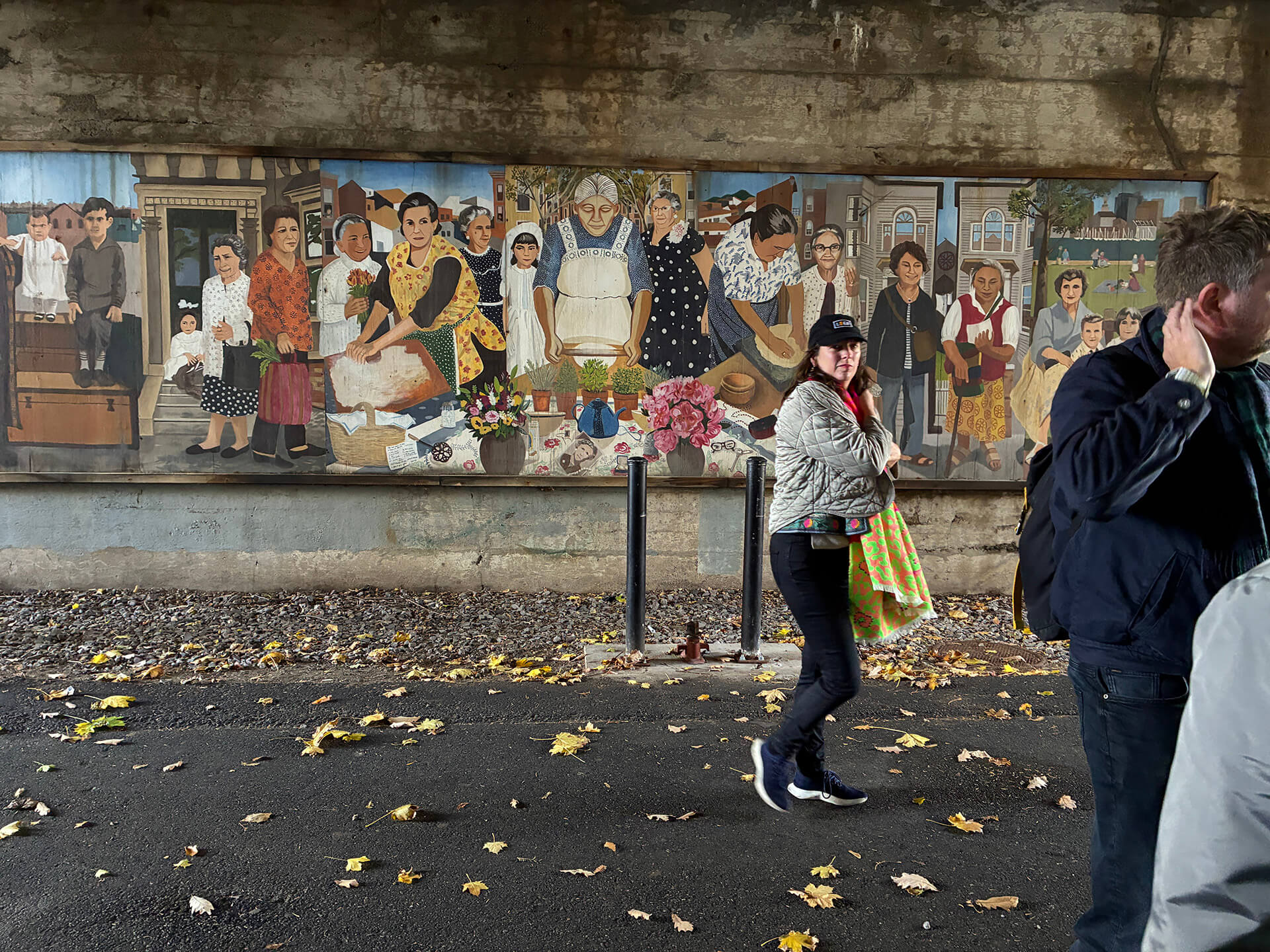 Paloma Streilitz in front of underpass mural showing the diversity of East Boston residents