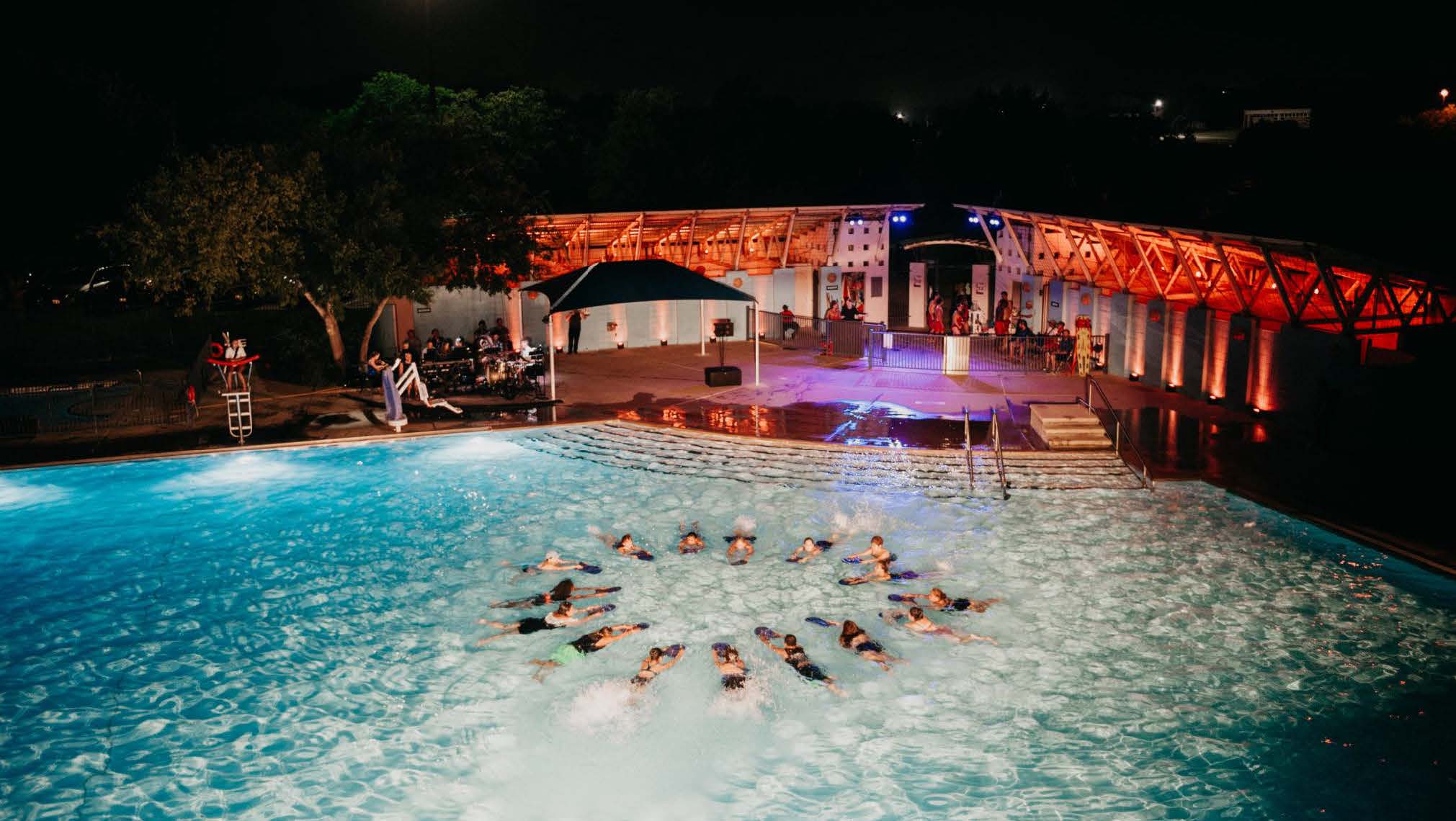 Synchronized swimmers in circular formation in pool at night.
